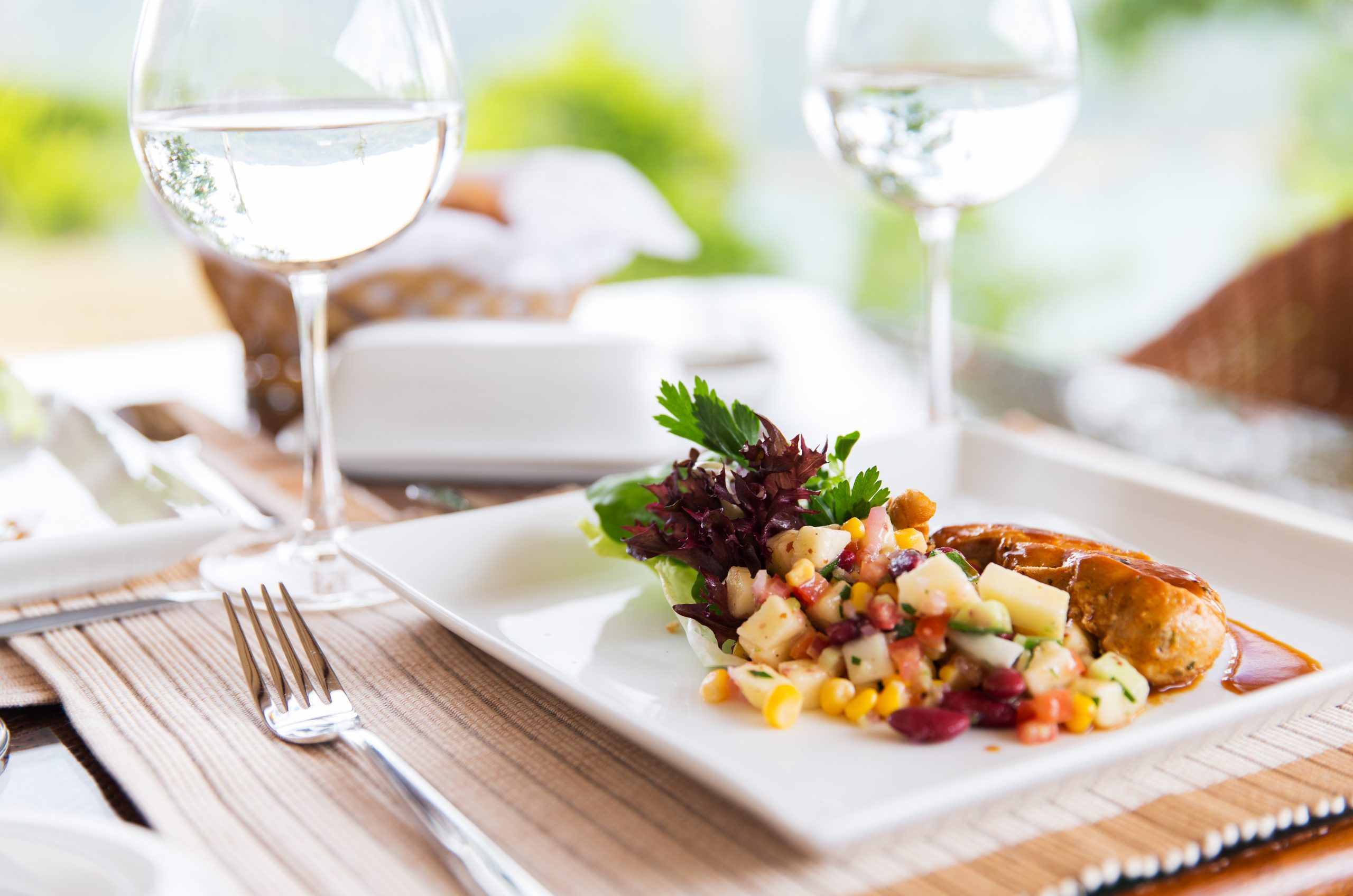 food, cooking and eating concept - close up of meat dish with garnish and water glasses on table at restaurant or home